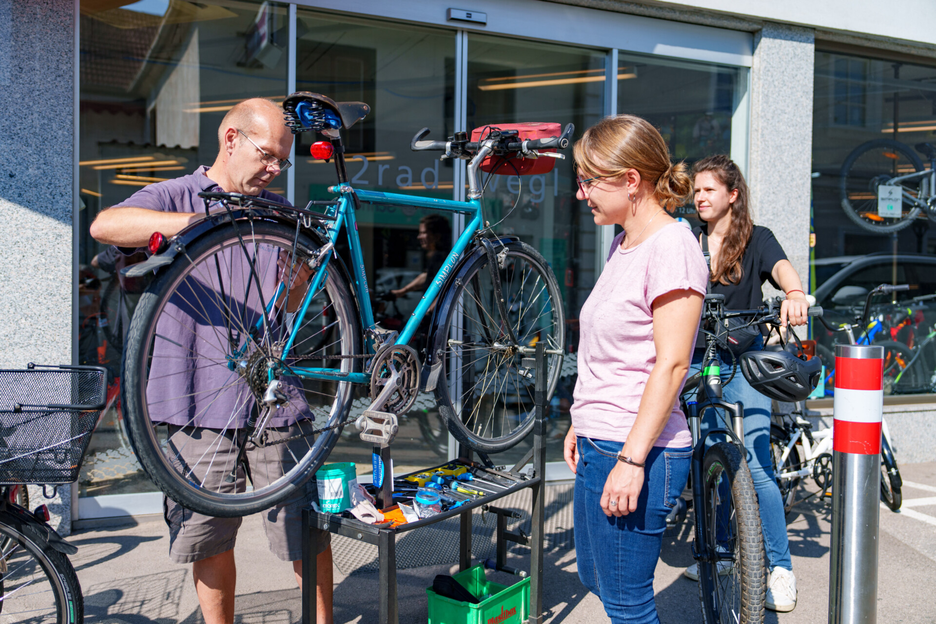 Radmechaniker arbeitet an Rad während Kundin zusieht