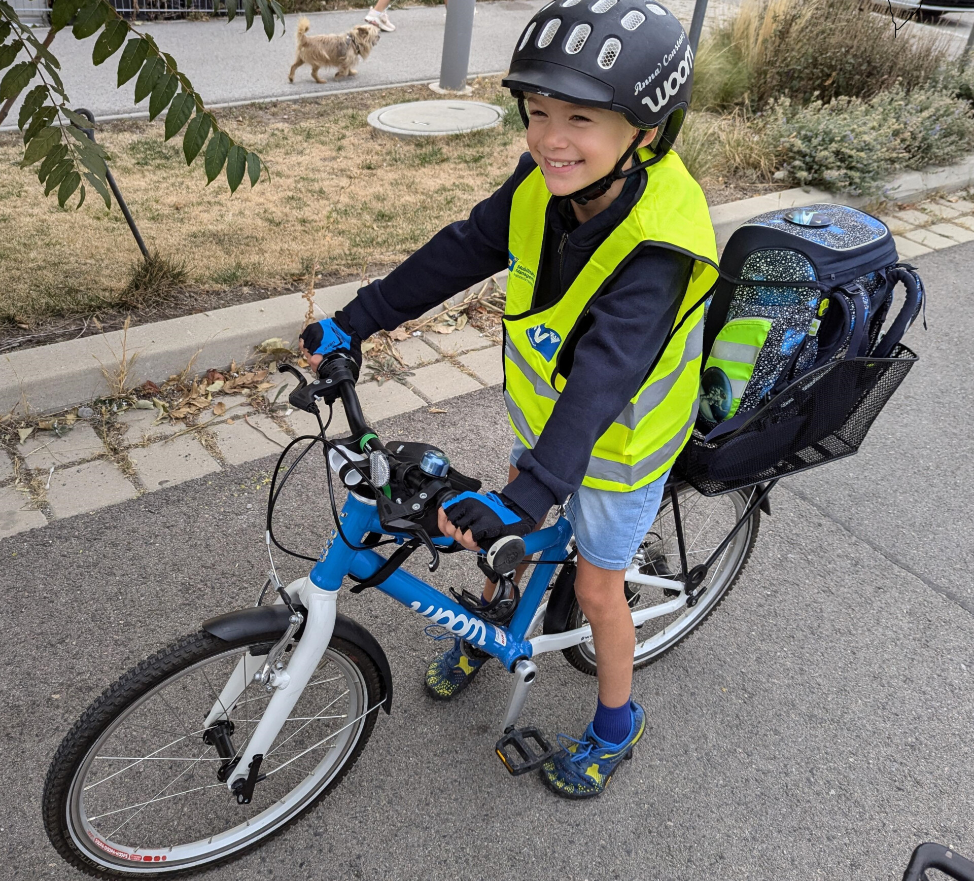 Kind auf dem Rad mit SchulRadBus Weste, Helm und Schultasche im Korb