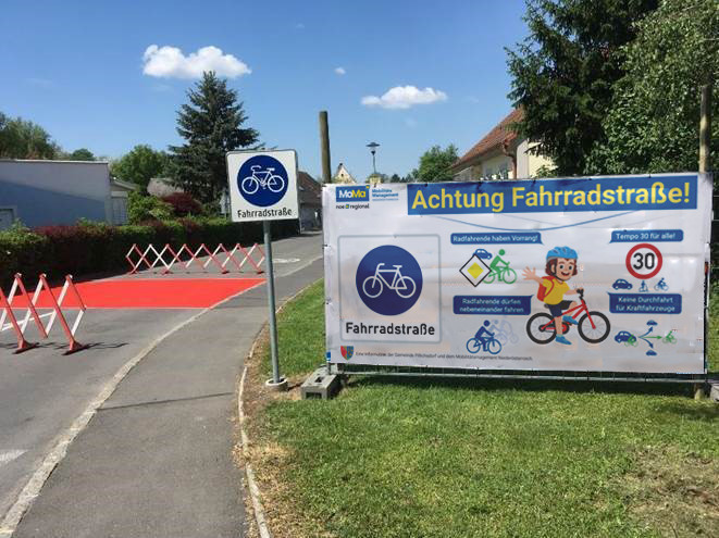 Straße mit großem Banner mit Regeln in der Fahrradstraße