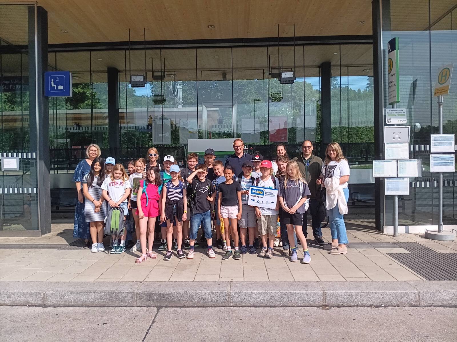 Gruppe von Kindern und Erwachsenen vor dem Bahnhof