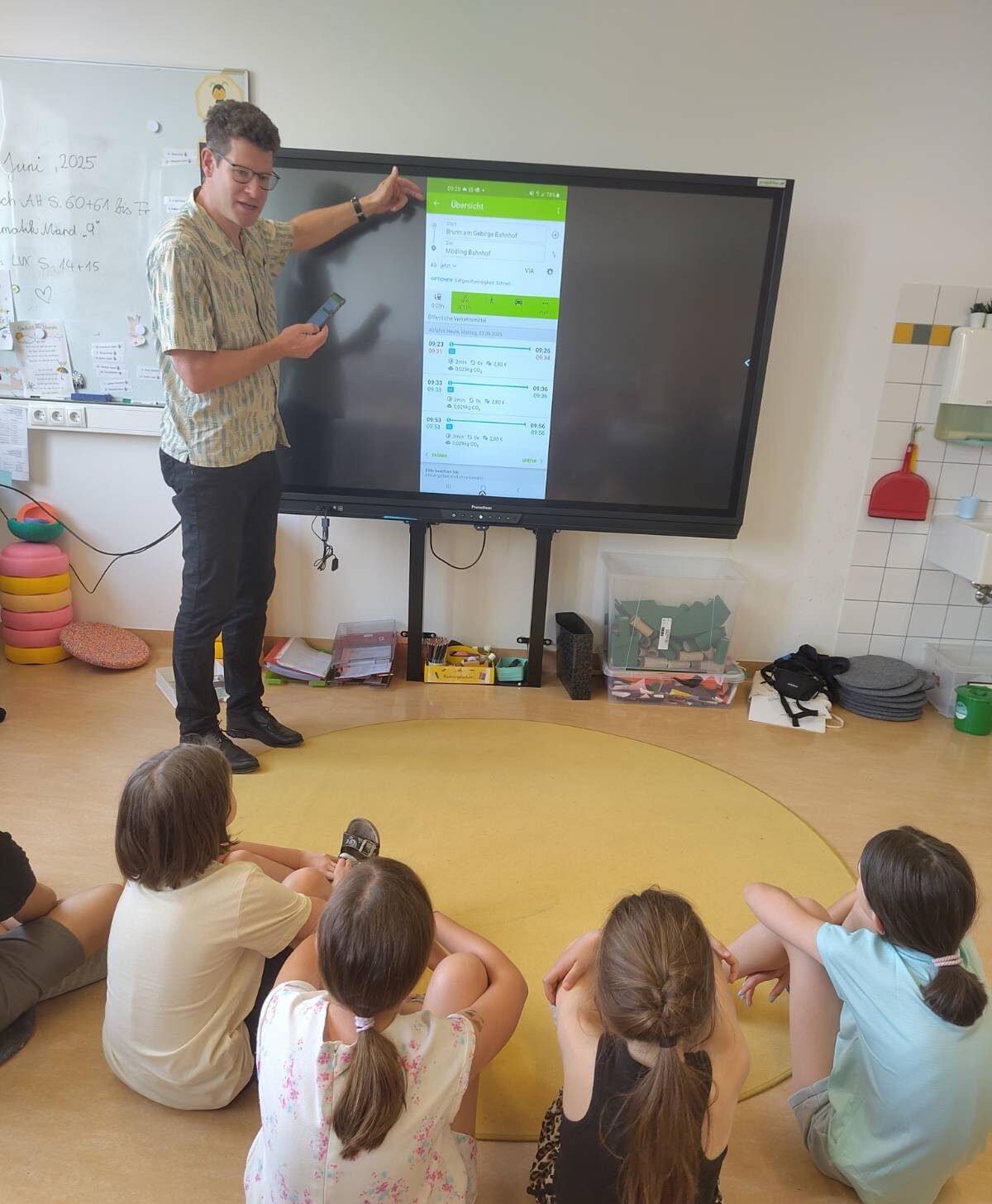 Mann erklärt Kindern VORAnachB App auf einem großen Bildschirm
