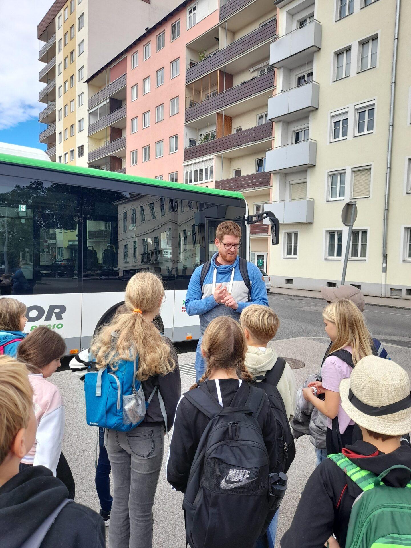 NÖVOG Busplaner Dominik Karas erklärt Kindern an einer Bushaltestelle wie der Busverkehr in Niederösterreich funktioniert