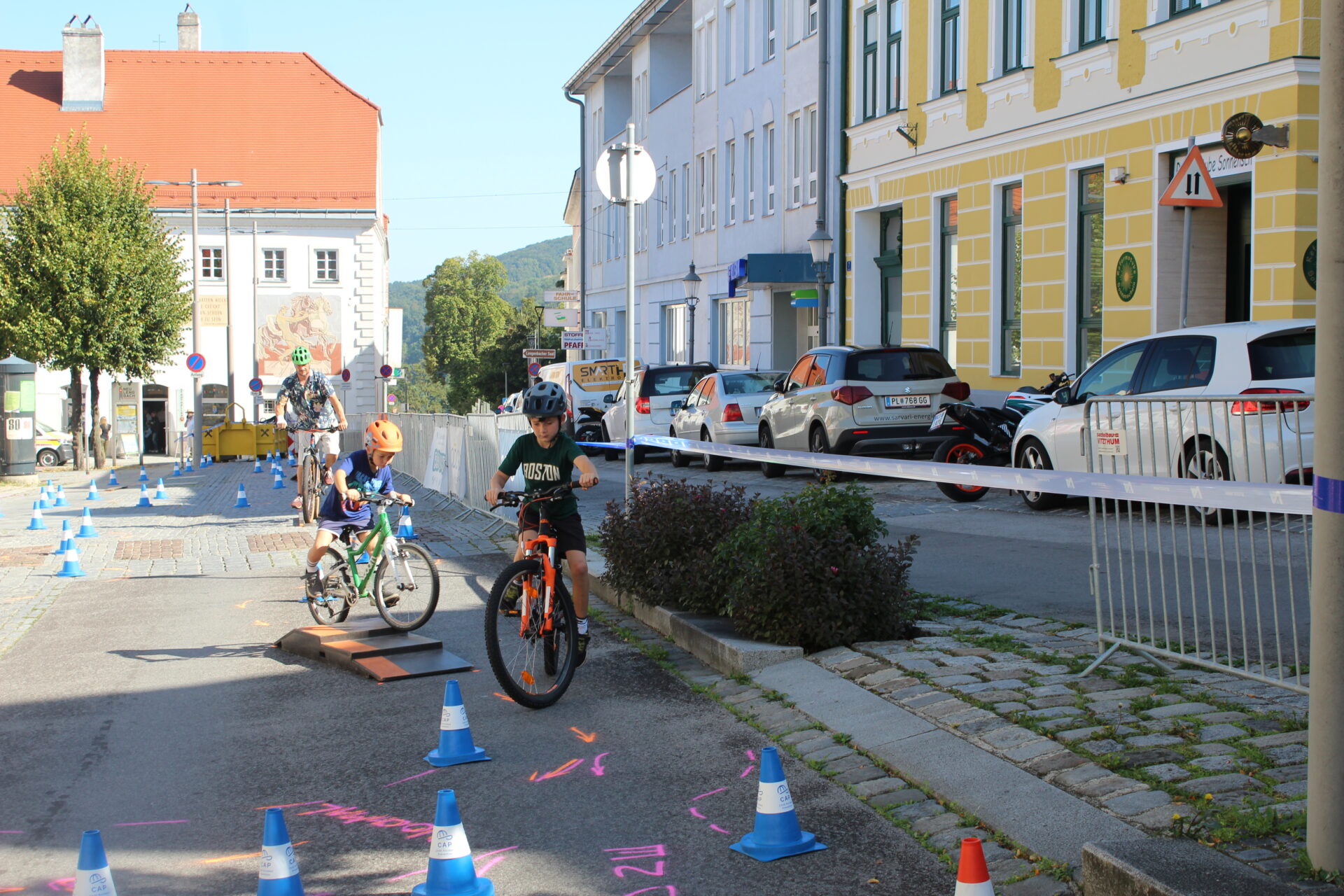 Mann mit zwei Kindern fährt mit dem Fahrrad einen Rad-Motorikparcours