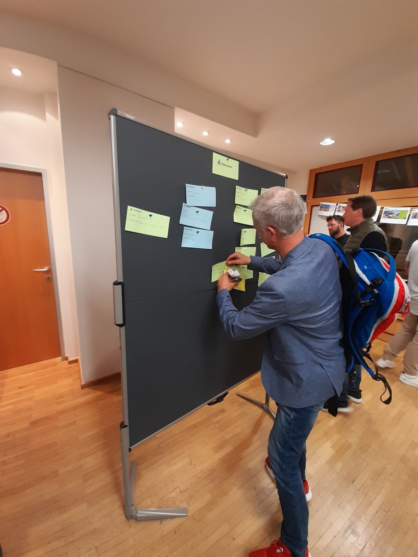Gemeindevertreter pinnt Kärtchen mit Projektinteresse an Pinnwand