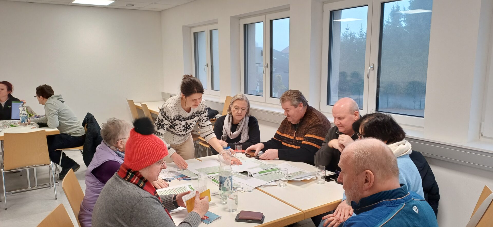 Menschen sitzen an einem Tisch über Fahrpläne gebeugt.