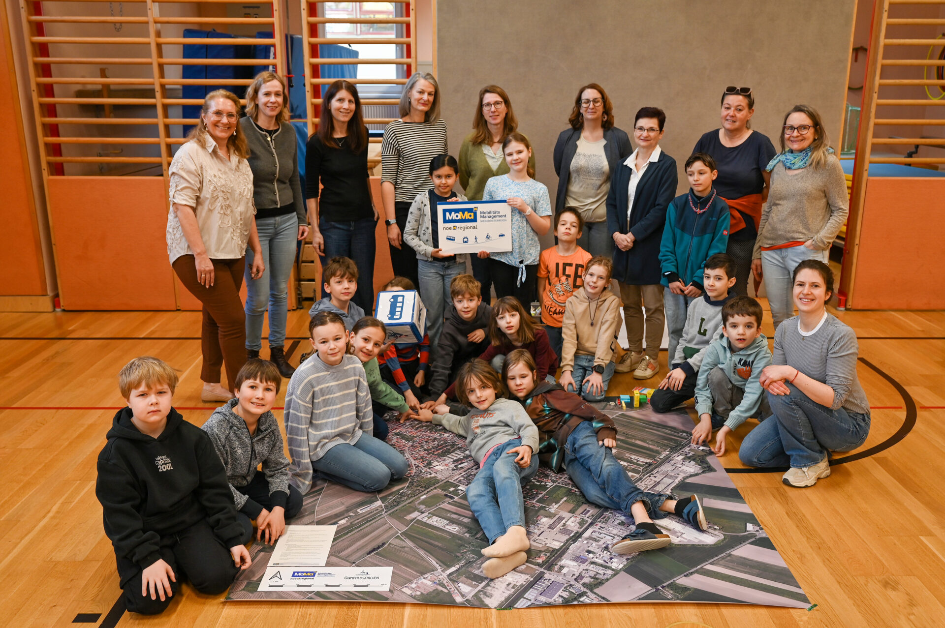 Kinder und Erwachsene stehen und sitzen vor großem Planteppich